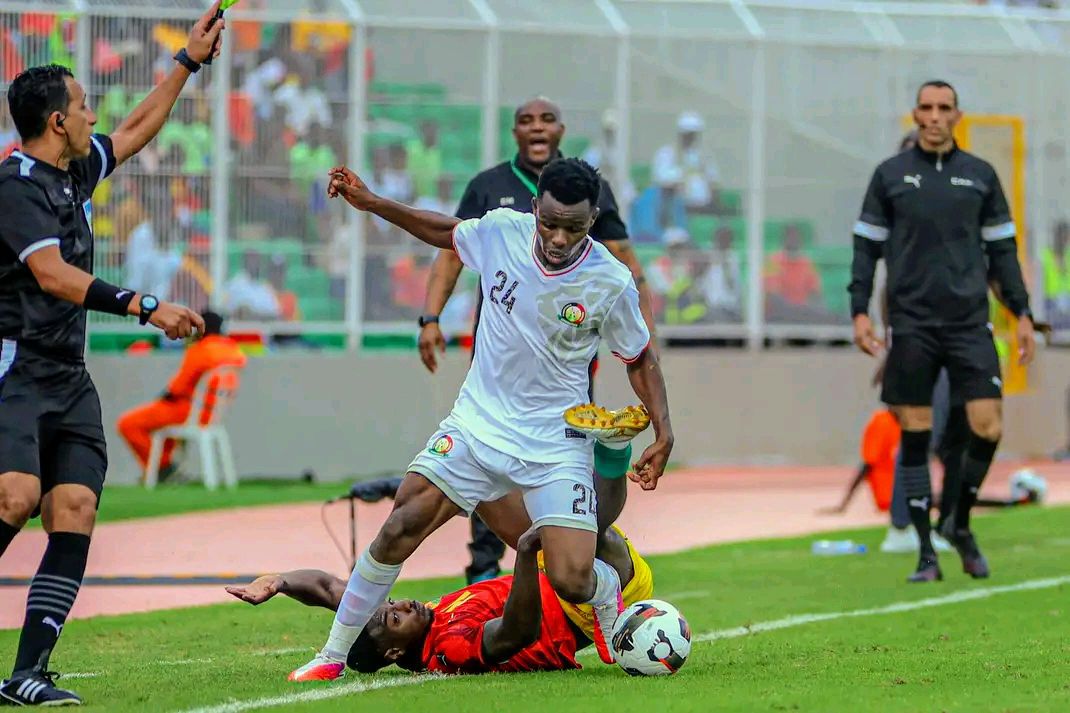 Ben Stanley Omondi challenges a Guinea player as Benni McCarthy watches